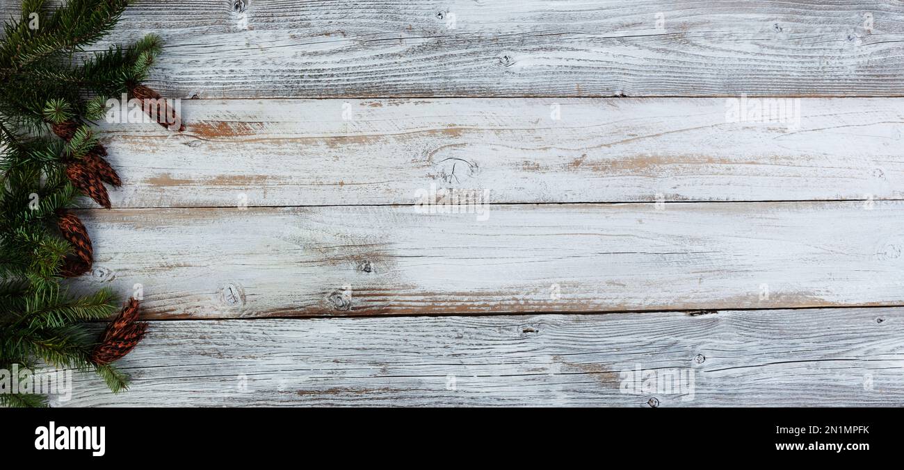 Decorazione natalizia con veri rami di abete che formano il bordo sinistro su sfondo bianco di legno invecchiato Foto Stock