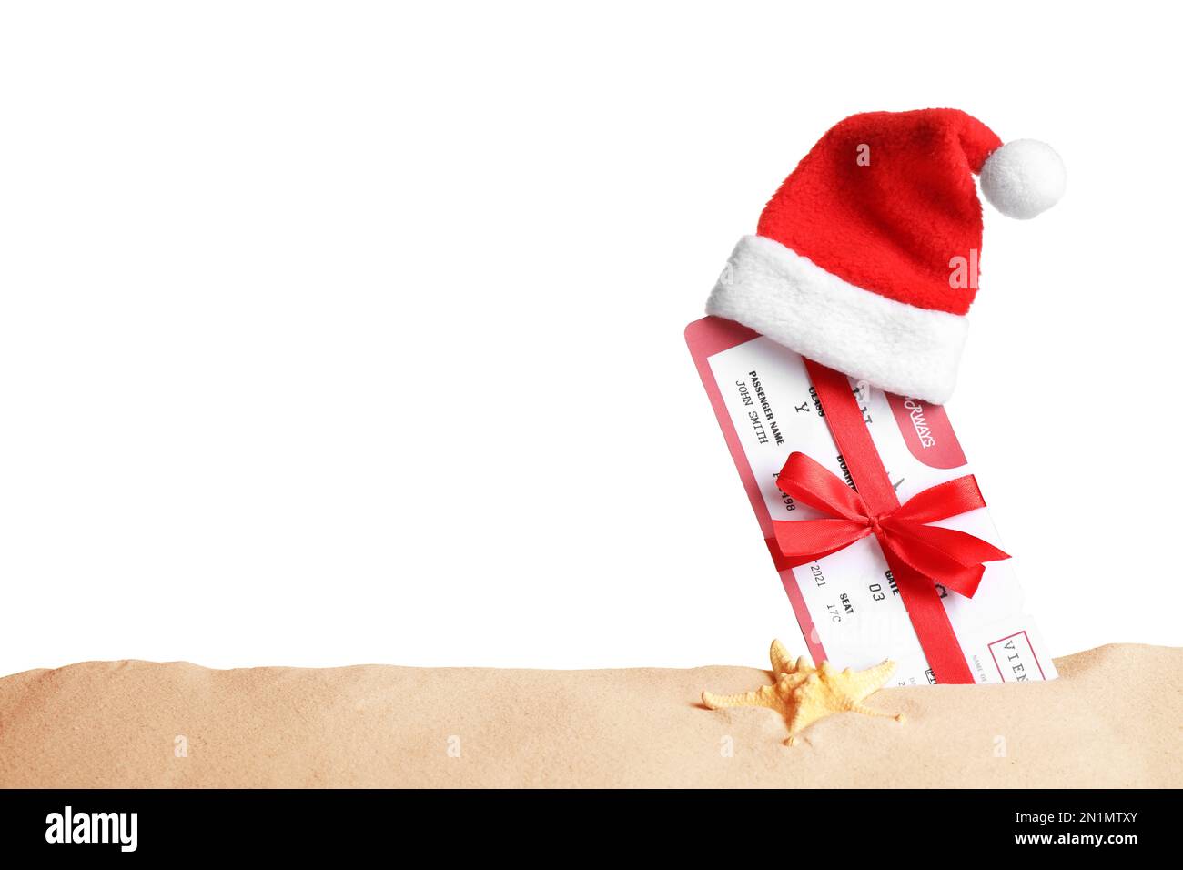 Biglietto aereo con arco rosso e cappello di Santa in sabbia vicino alle stelle marine, spazio per il testo. Vacanze di Natale Foto Stock