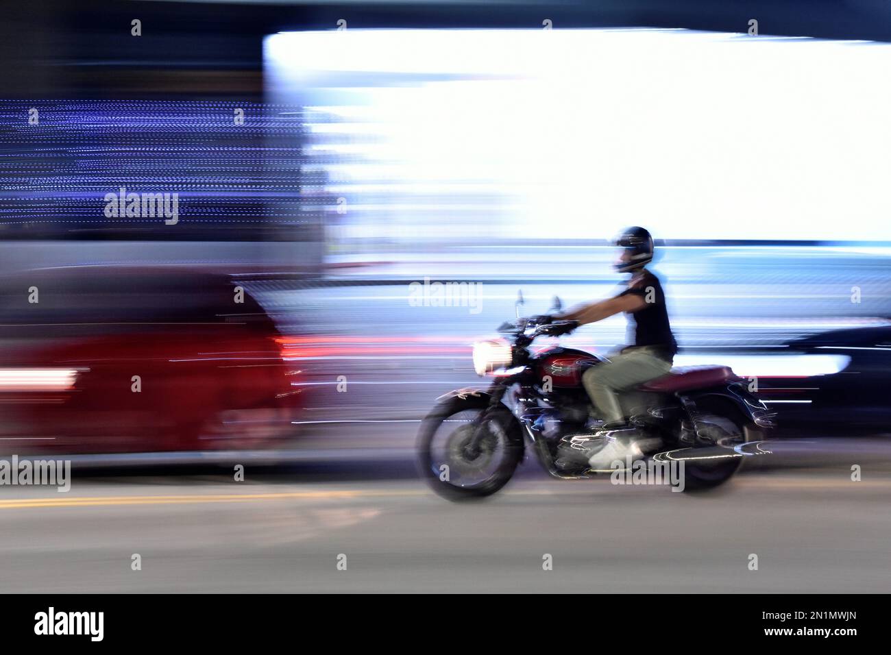 Uomo che guida una moto di notte. Tecnica fotografica panning. Foto Stock