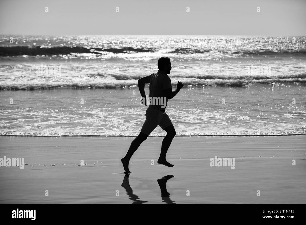 silhouette di uomo sportivo sprinting sulla spiaggia all'aperto, obiettivo Foto Stock