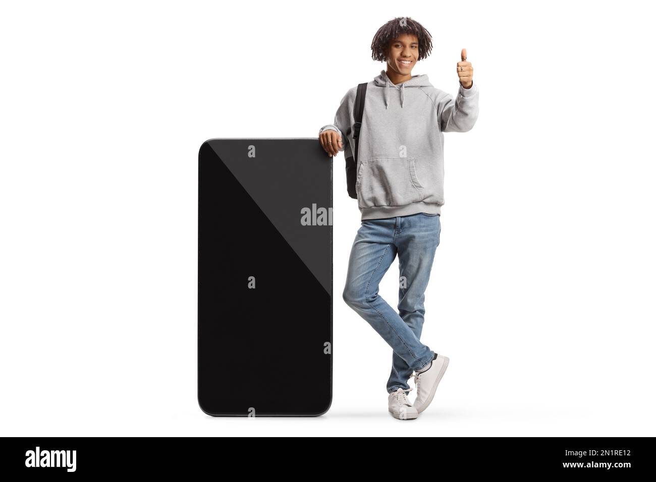 Giovane studente afro-americano appoggiato su un grande telefono cellulare e gesturing pollici isolato su sfondo bianco Foto Stock