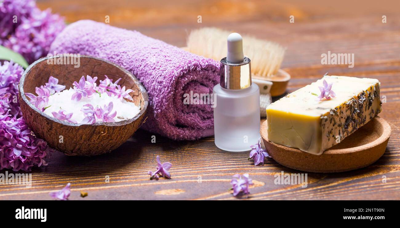 Ambiente benessere con sapone naturale, olio essenziale di lilla, sale marino e pietre da massaggio con morbidi asciugamani di cotone per coccolarsi Foto Stock