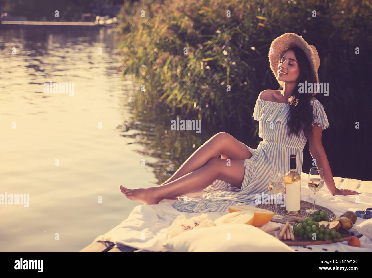 Giovane donna che trascorre del tempo sul molo al picnic Foto Stock