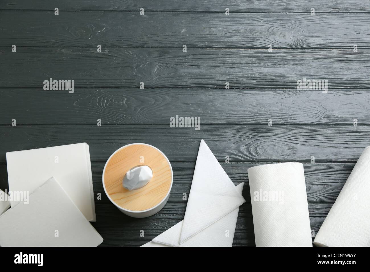 Tovaglioli puliti, scatola con fazzolettini e rotoli di tovaglioli di carta su un tavolo di legno grigio, piatto. Spazio per il testo Foto Stock
