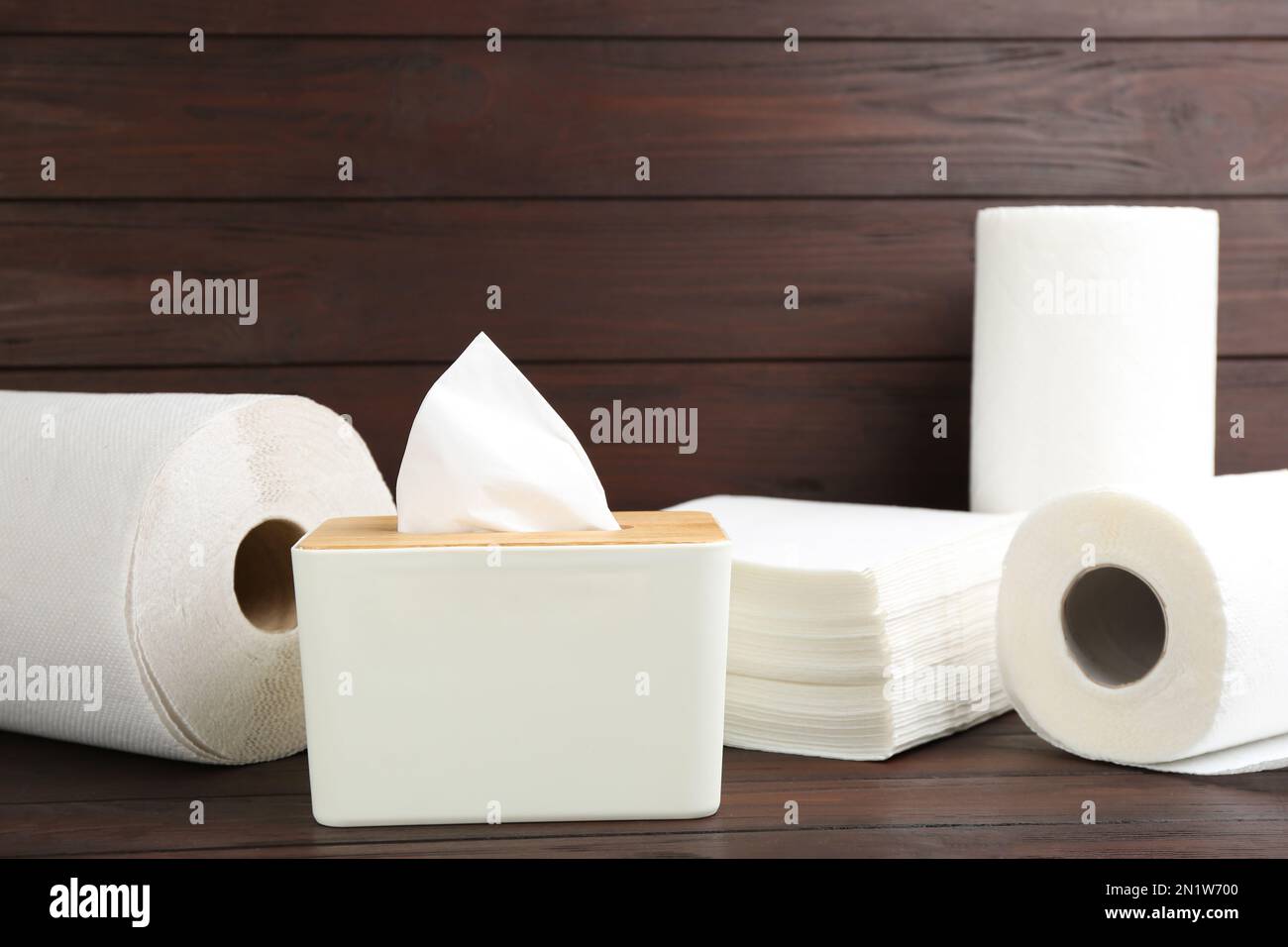 Tovaglioli puliti, scatola con fazzolettini e rotoli di tovaglioli di carta su tavolo di legno Foto Stock