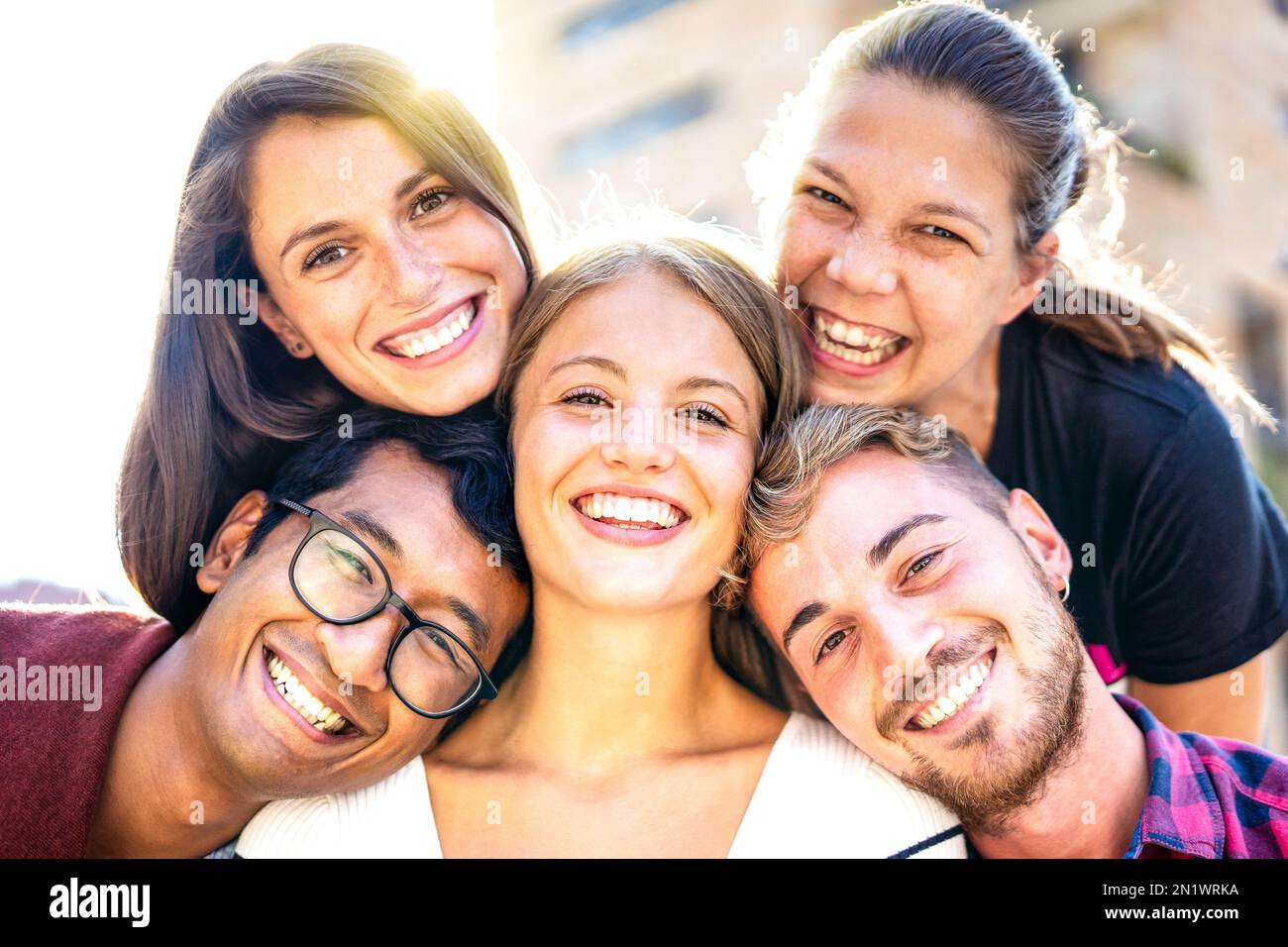 Ragazzi e ragazze multiculturali che si affiancano al selfie con retroilluminazione - concetto di stile di vita felice mileniale su giovani amici diversi che hanno divertimento giorno insieme Foto Stock