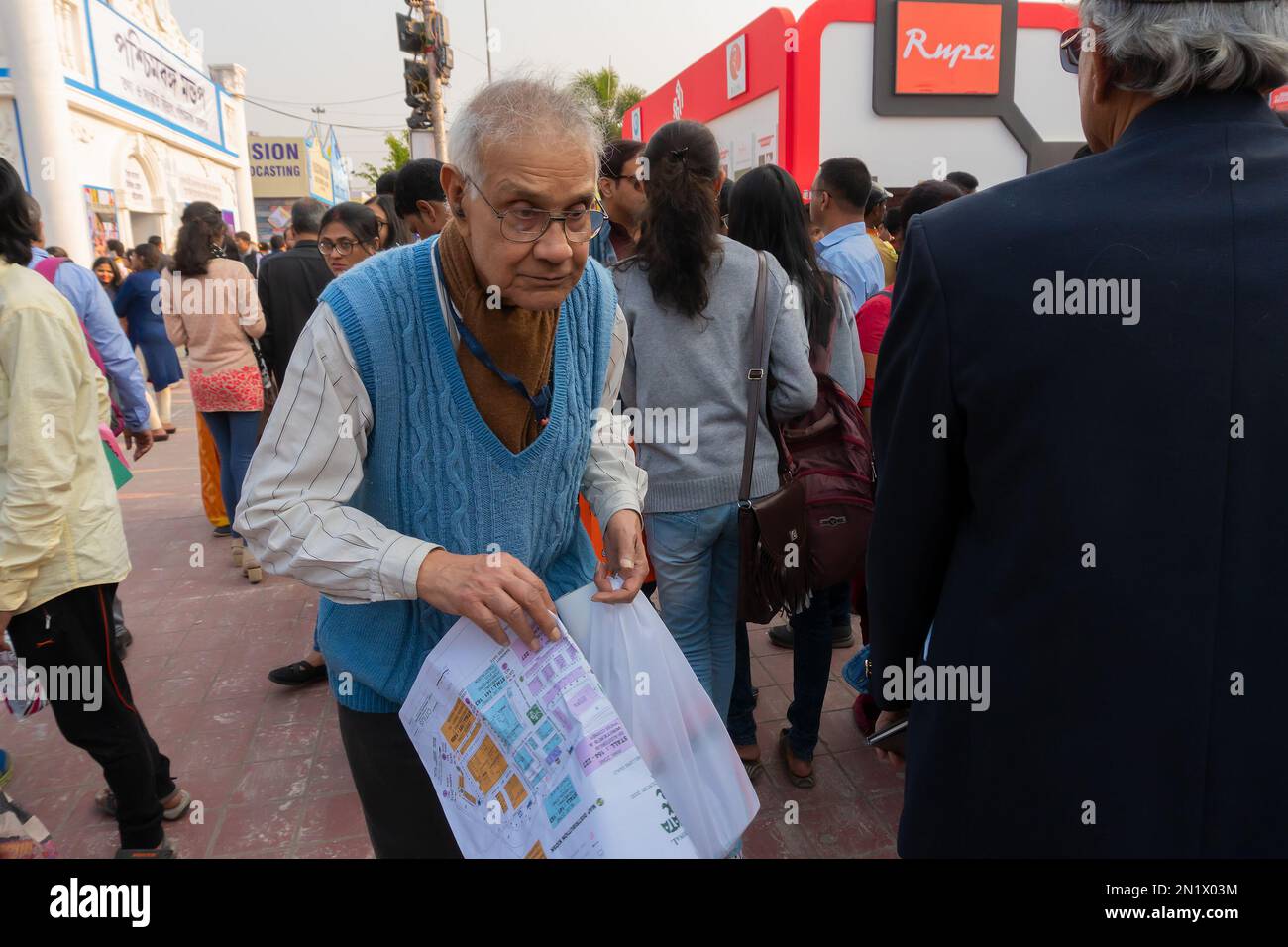Calcutta, Bengala Occidentale, India - 2 febbraio 2020: Vecchio amante del libro alla ricerca di libri preferiti con una mappa di terreno della fiera del libro in mano al Bookfair. Foto Stock
