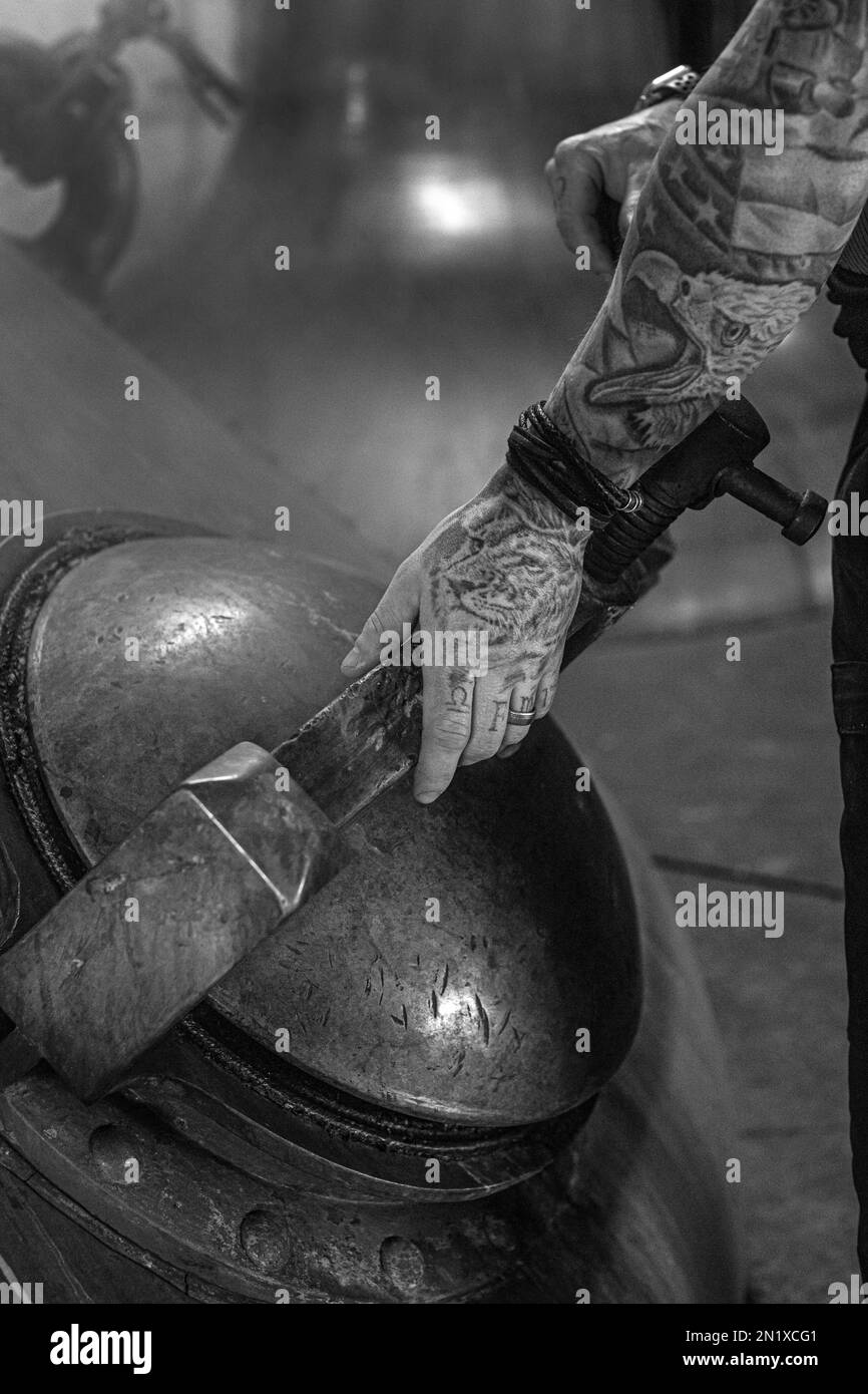 Scozia, Campbeltown, Springbank Distillery, primo piano dell'operatore della distilleria con braccio tatooed che chiude la porta di un uomo dalla pentola di rame ancora . Foto Stock