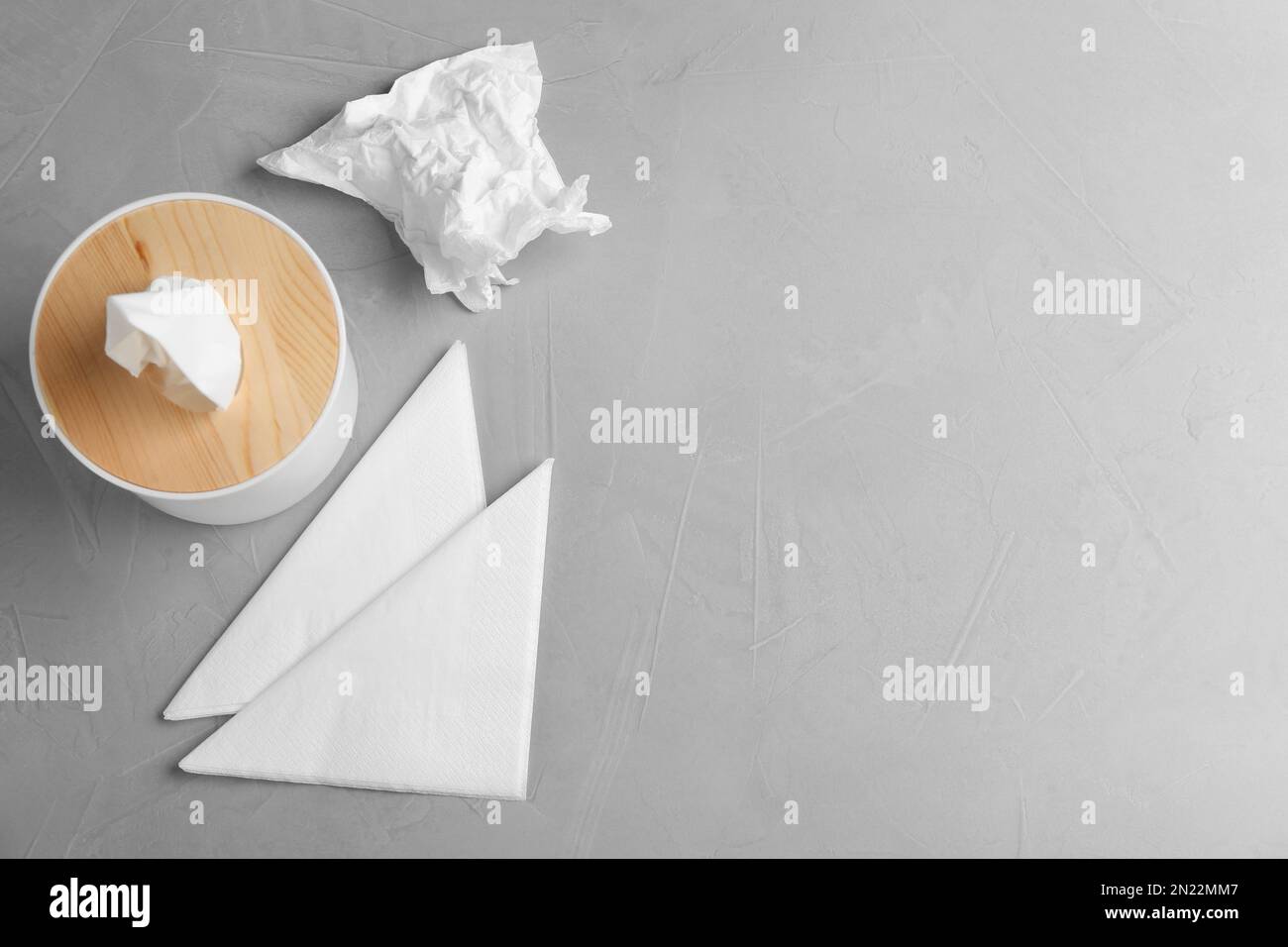 Scatola di legno con fazzolettini e tovaglioli su un tavolo leggero, piatto. Spazio per il testo Foto Stock