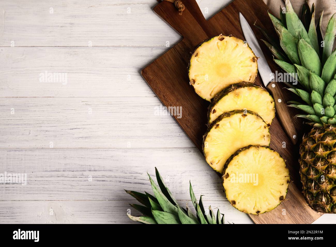 Fette di ananas fresco su tavolo di legno bianco, piatto. Spazio per il testo Foto Stock