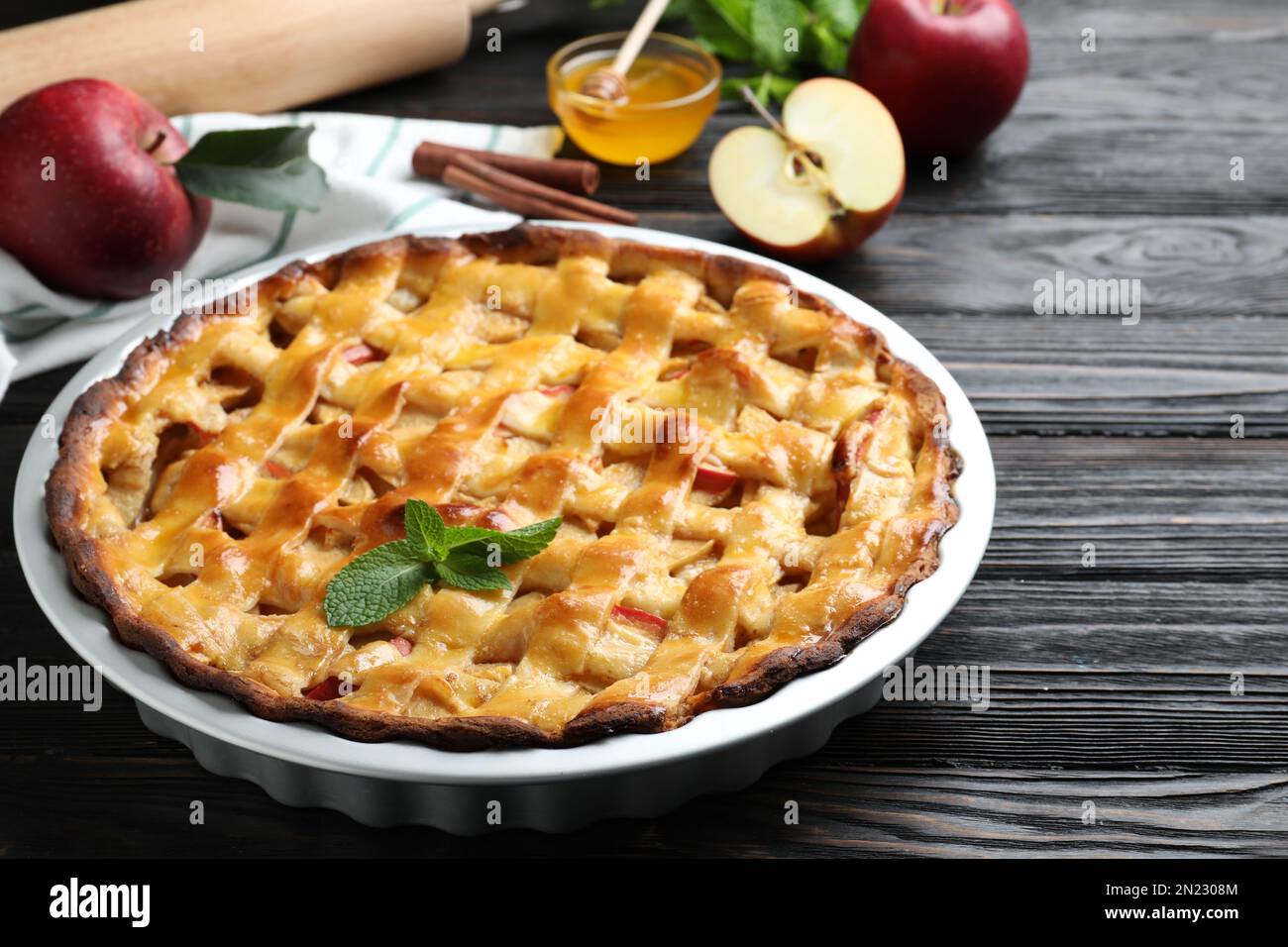 Tradizionale torta di mele con menta su tavolo di legno nero Foto Stock