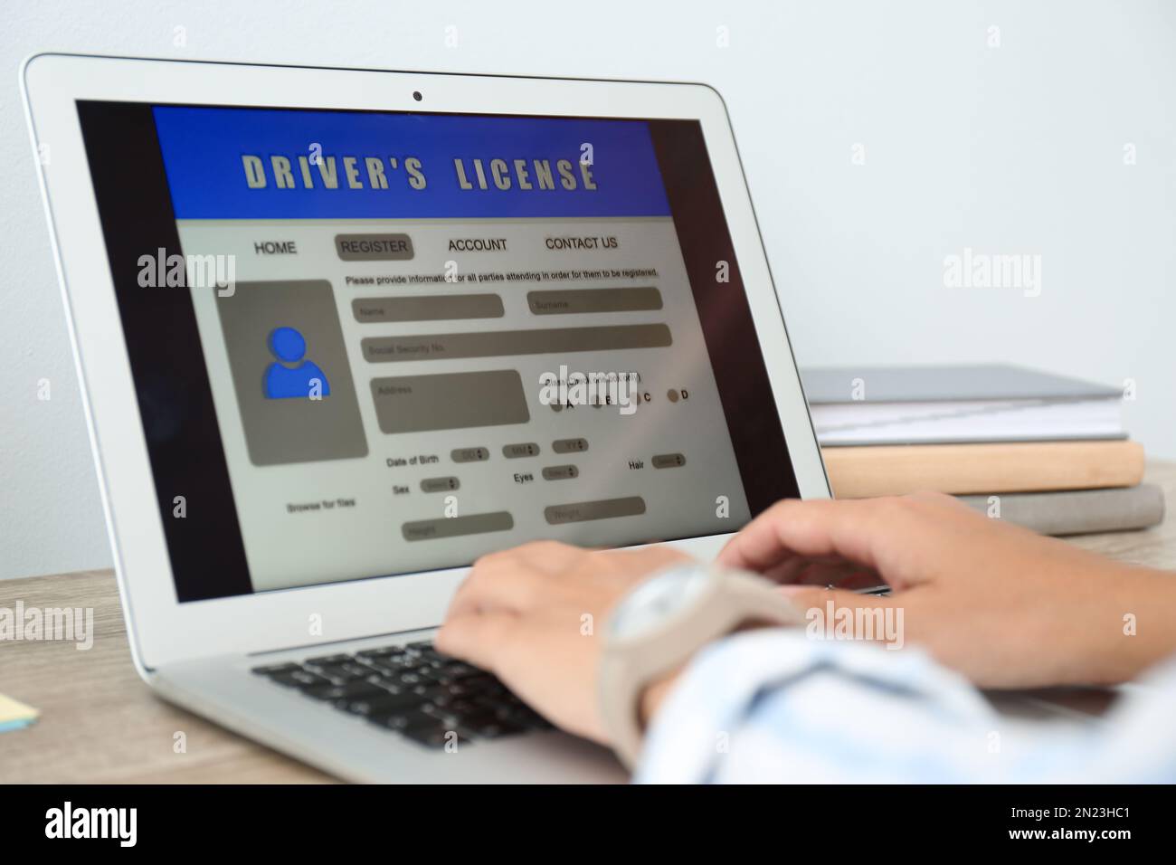Donna che utilizza il computer portatile per compilare il modulo di domanda di patente di guida al tavolo in ufficio, in primo piano Foto Stock
