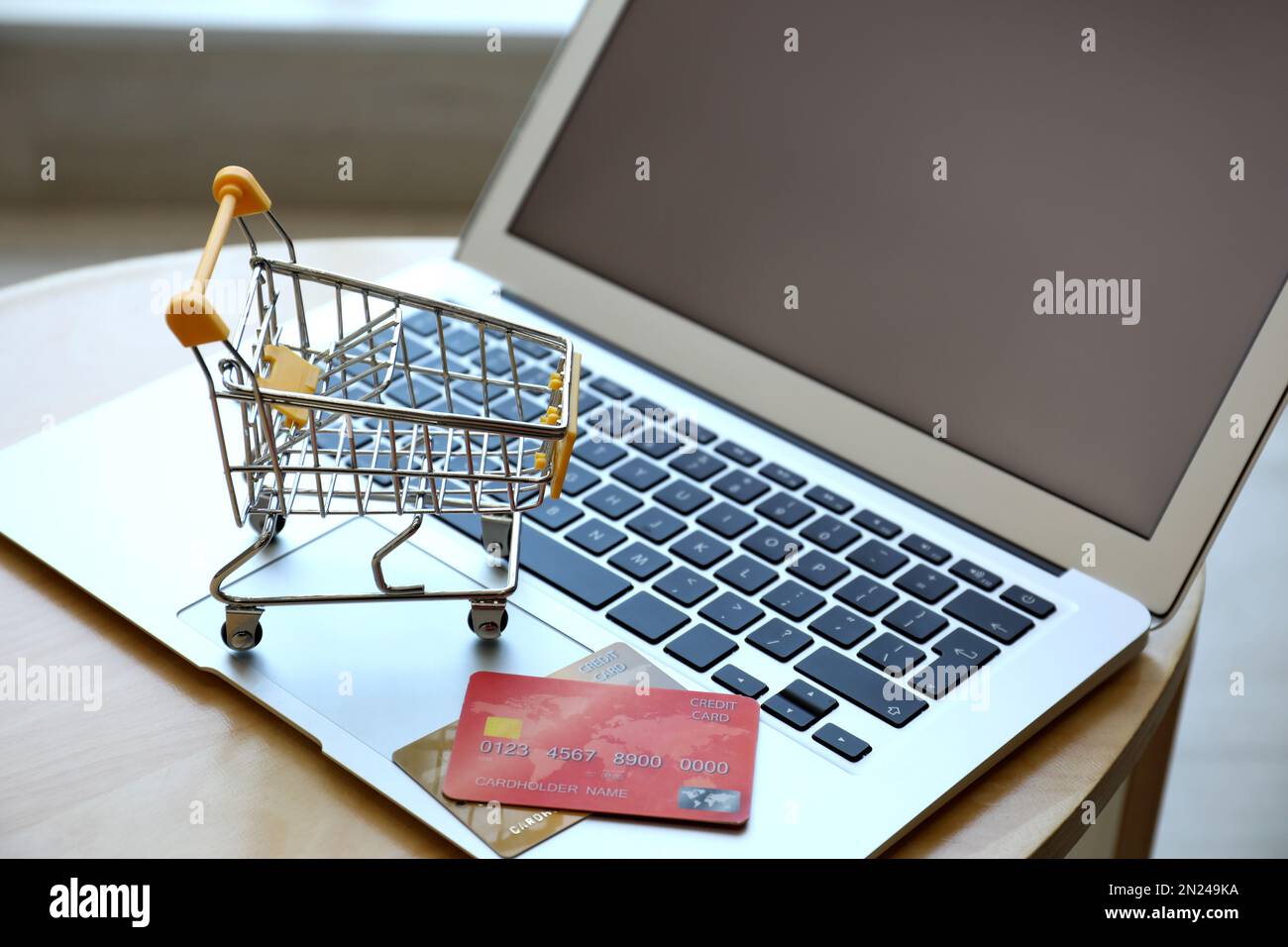Shopping su Internet. Computer portatile, piccolo carrello e carte