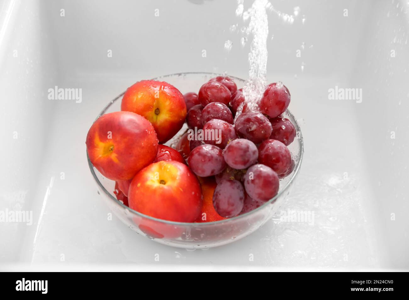 Lavare in ciotola, sotto acqua di rubinetto, uva fresca e nettarine Foto Stock