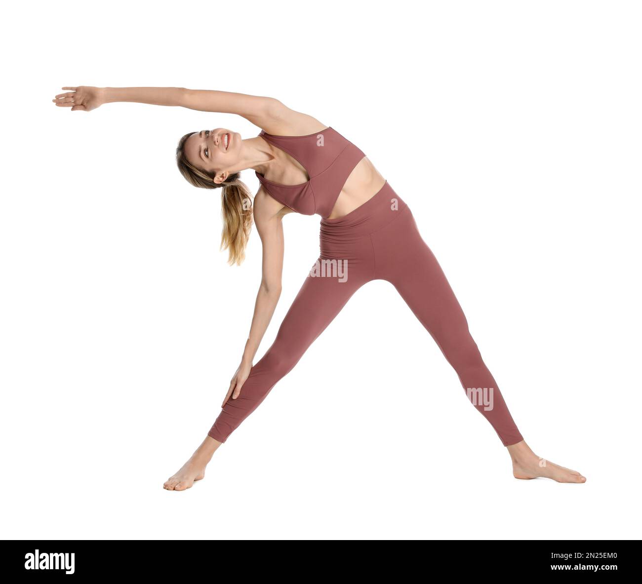 Giovane donna in abbigliamento sportivo che pratica yoga su sfondo bianco Foto Stock