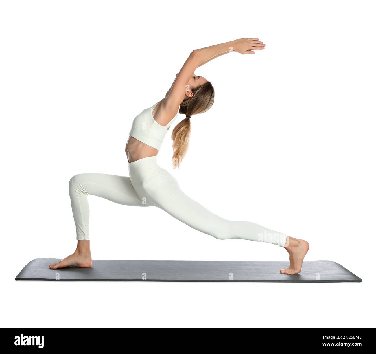 Giovane donna in abbigliamento sportivo che pratica yoga su sfondo bianco Foto Stock