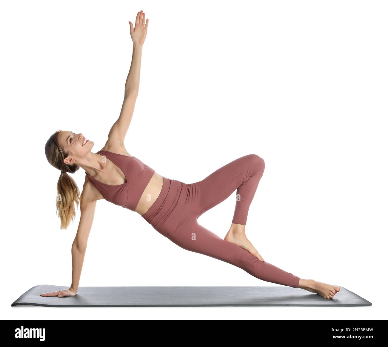 Giovane donna in abbigliamento sportivo che pratica yoga su sfondo bianco Foto Stock