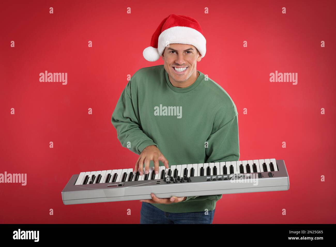 Uomo in berretto Santa che gioca sintetizzatore su sfondo rosso. Musica di Natale Foto Stock