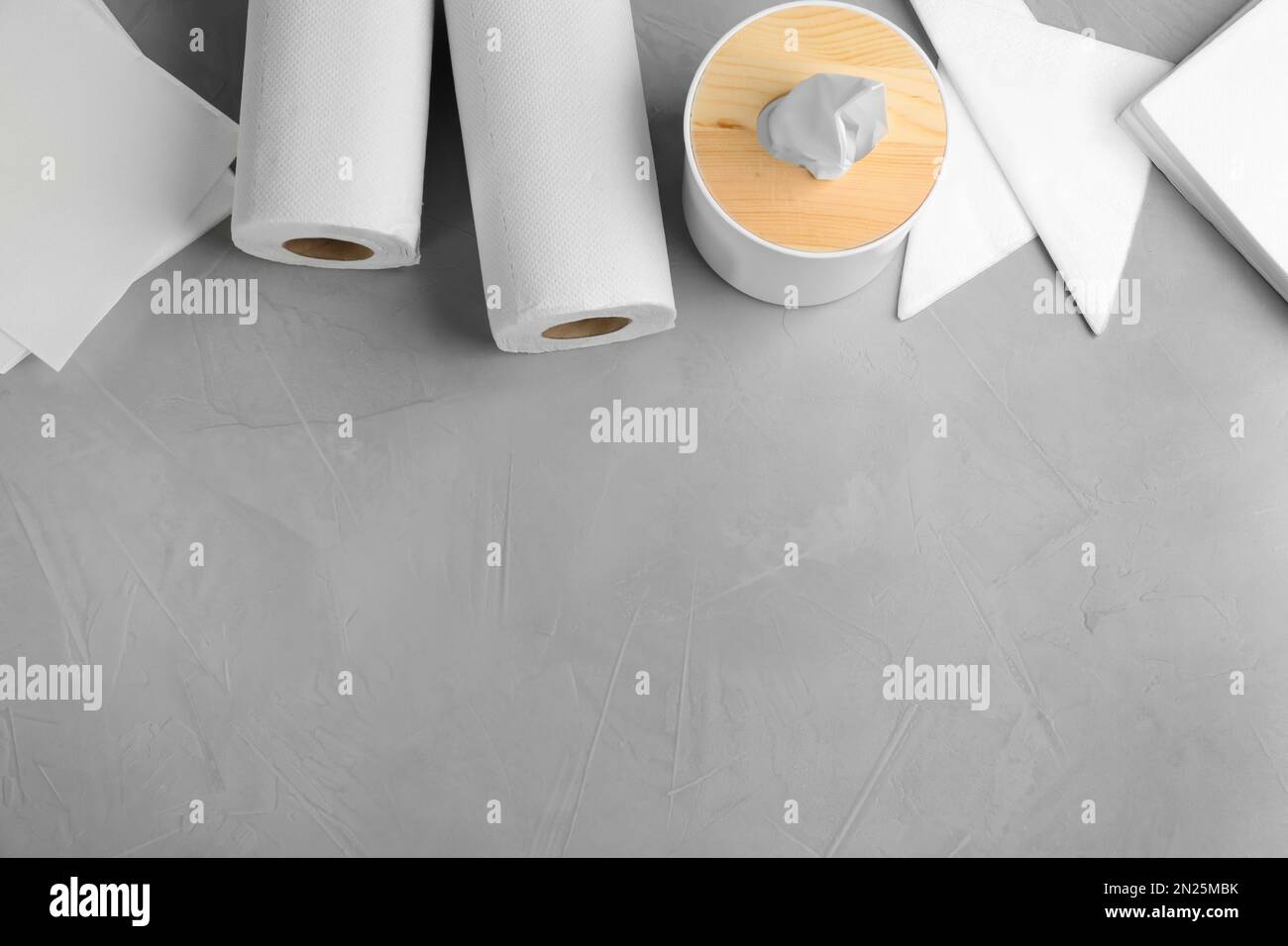 Tovaglioli puliti, scatola con fazzoletti e rotoli di tovaglioli di carta su un tavolo leggero, piatto. Spazio per il testo Foto Stock