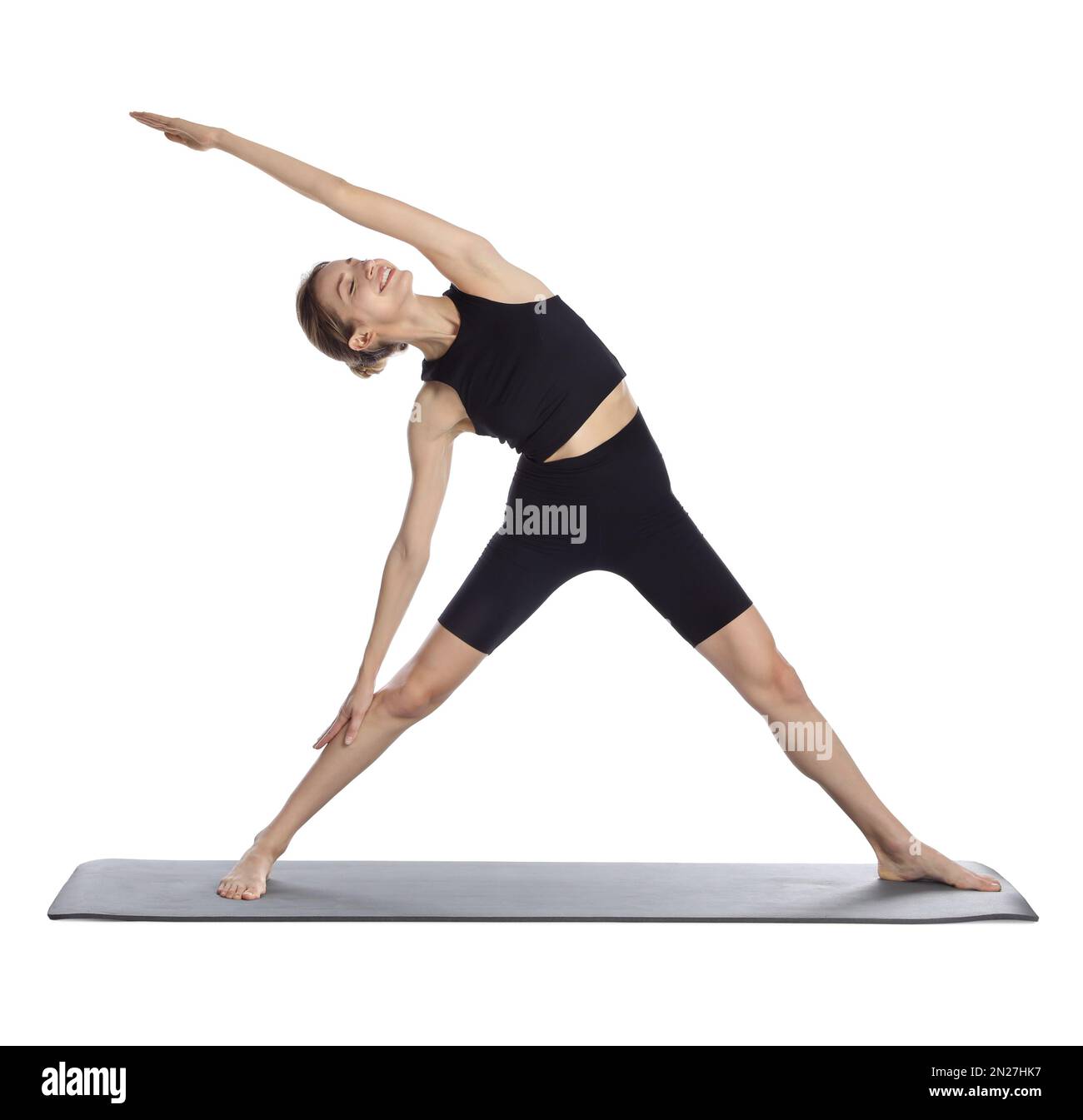 Giovane donna in abbigliamento sportivo che pratica yoga su sfondo bianco Foto Stock