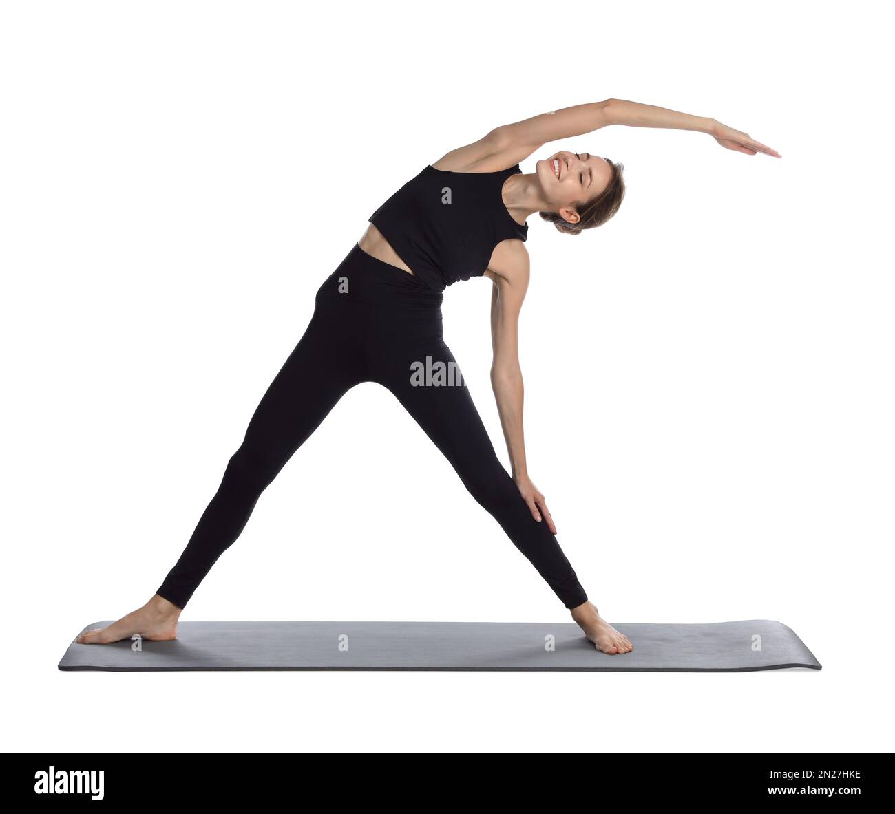 Giovane donna in abbigliamento sportivo che pratica yoga su sfondo bianco Foto Stock