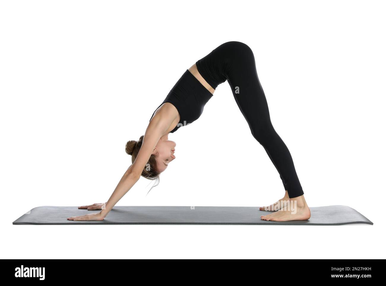 Giovane donna in abbigliamento sportivo che pratica yoga su sfondo bianco Foto Stock