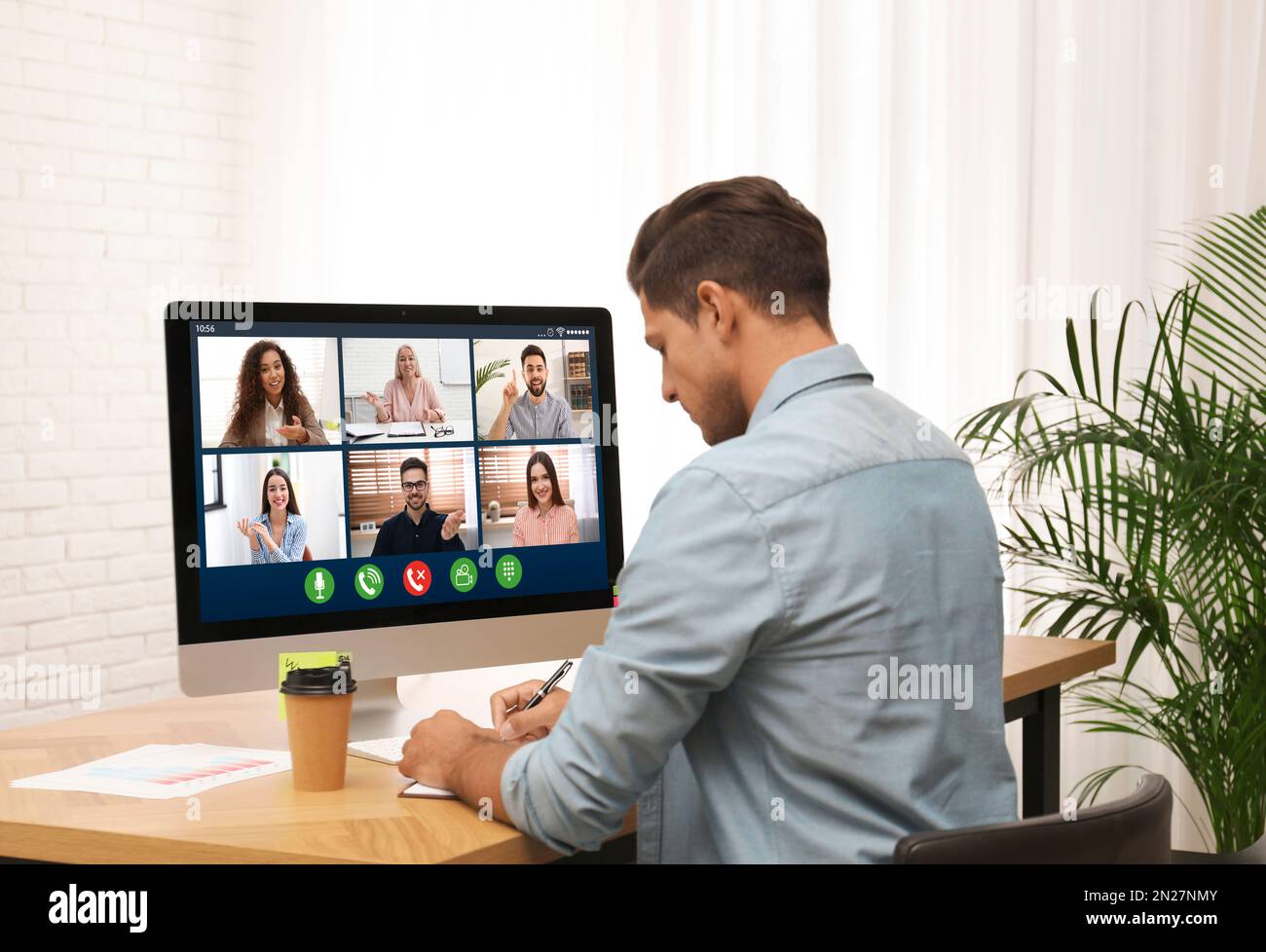 Uomo che ha una chat video con i colleghi al tavolo in ufficio. Lavoro di squadra Foto Stock
