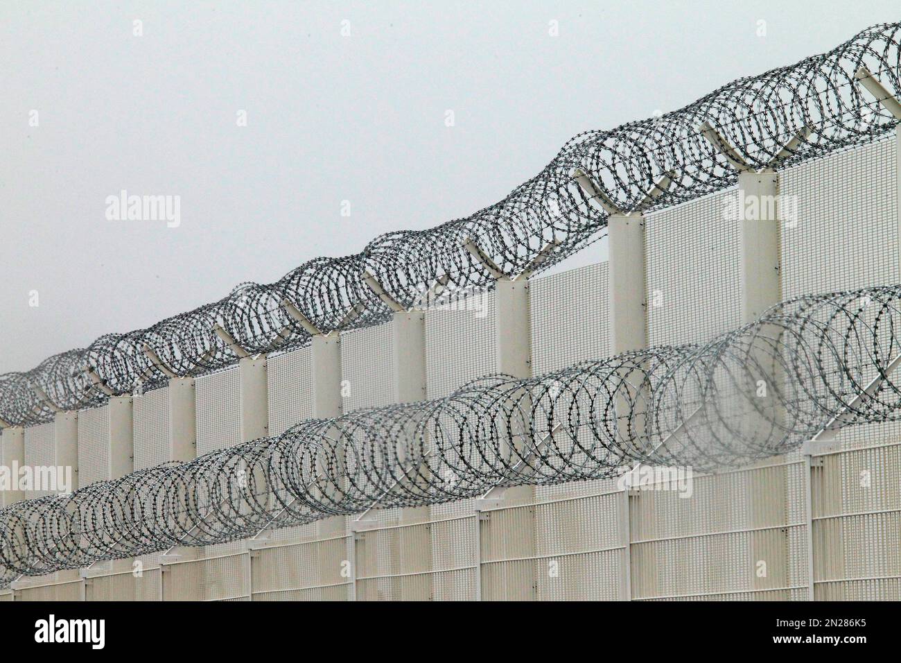 A razor-wired fence above the port of Calais, northern France, Wednesday, June 3, 2015. Each night, the Calais migrants try to slip unnoticed onto trucks crossing the channel on ferries or through the Eurotunnel beneath the channel. In a cat-and-mouse game with police, they dart across highways and pray for traffic jams, when it’s easier to sneak onto slow-moving trucks. (AP Photo/Michel Spingler) Foto Stock