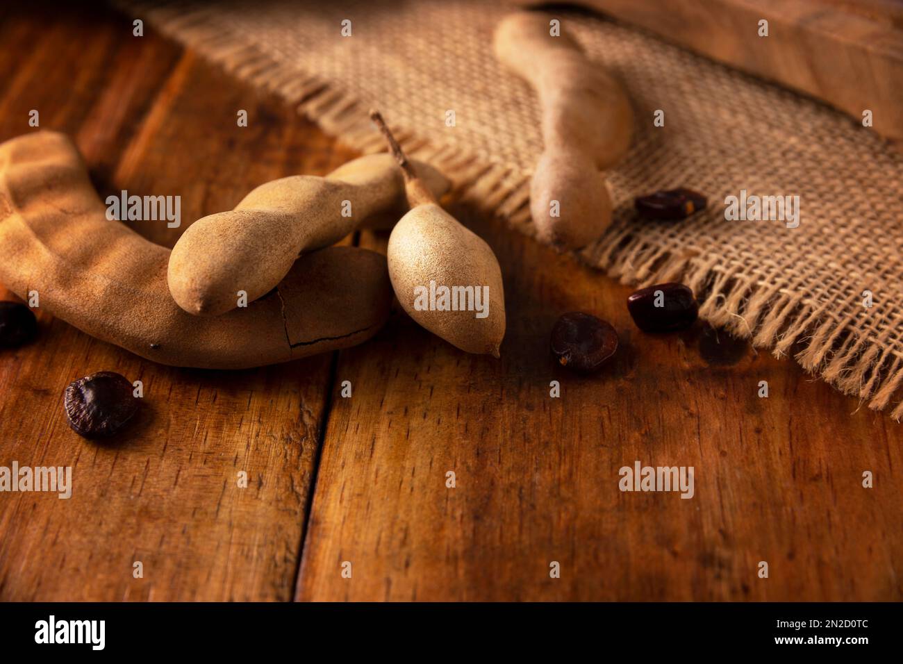 Tamarind frutta (Tamarindus indica) su tavola rustica di legno. Frutta tropicale molto apprezzata in molti paesi del mondo. Immagine di primo piano. Foto Stock