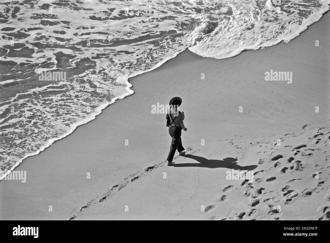 Donna con cappello sulla spiaggia solitaria sul mare dall'alto, Algave, Portogallo Foto Stock