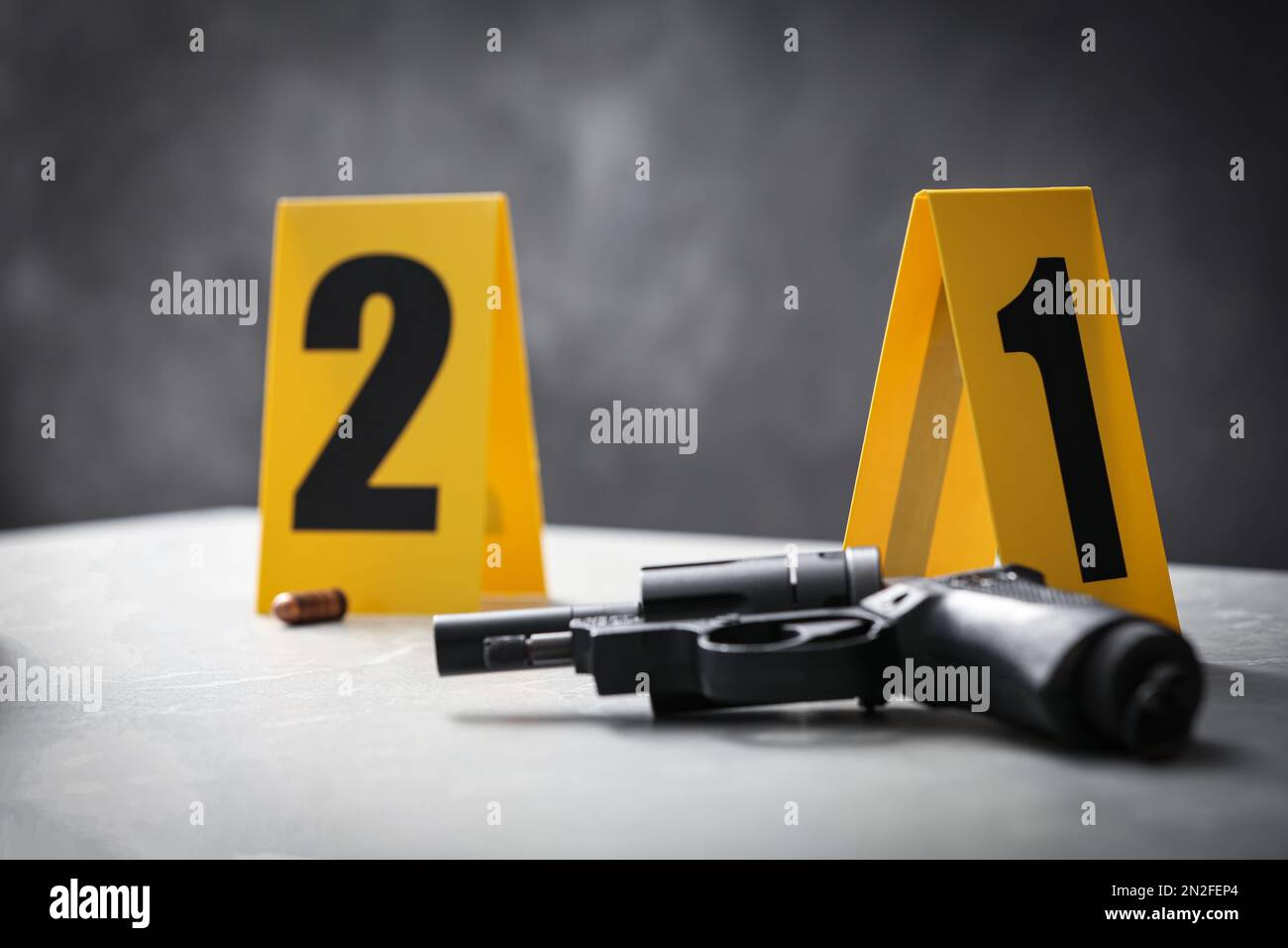 Pennarelli per pistola e scena del crimine su un tavolo in marmo grigio chiaro, primo piano Foto Stock