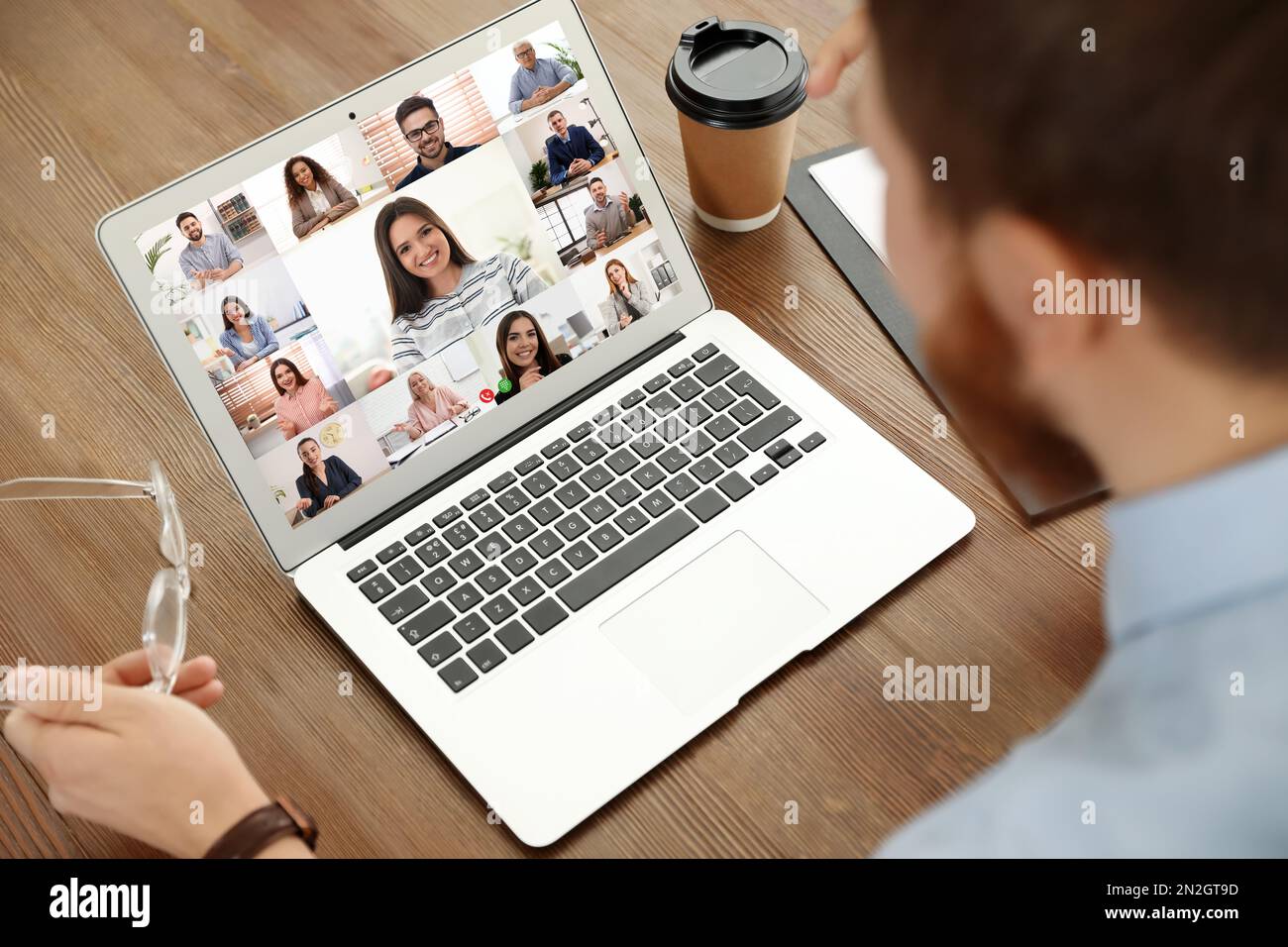 Uomo che ha video chat con la squadra a tavola, primo piano Foto Stock