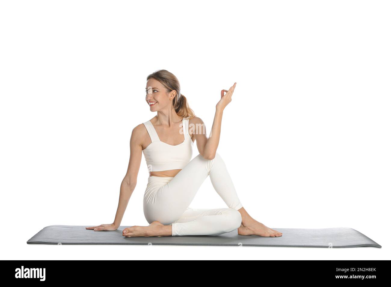 Giovane donna in abbigliamento sportivo che pratica yoga su sfondo bianco Foto Stock