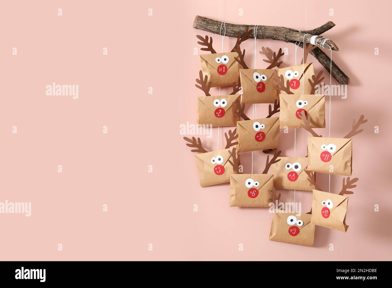 Regali in buste con facce di cervo appese su una parete rosa, spazio per il testo. Calendario dell'avvento di Natale Foto Stock