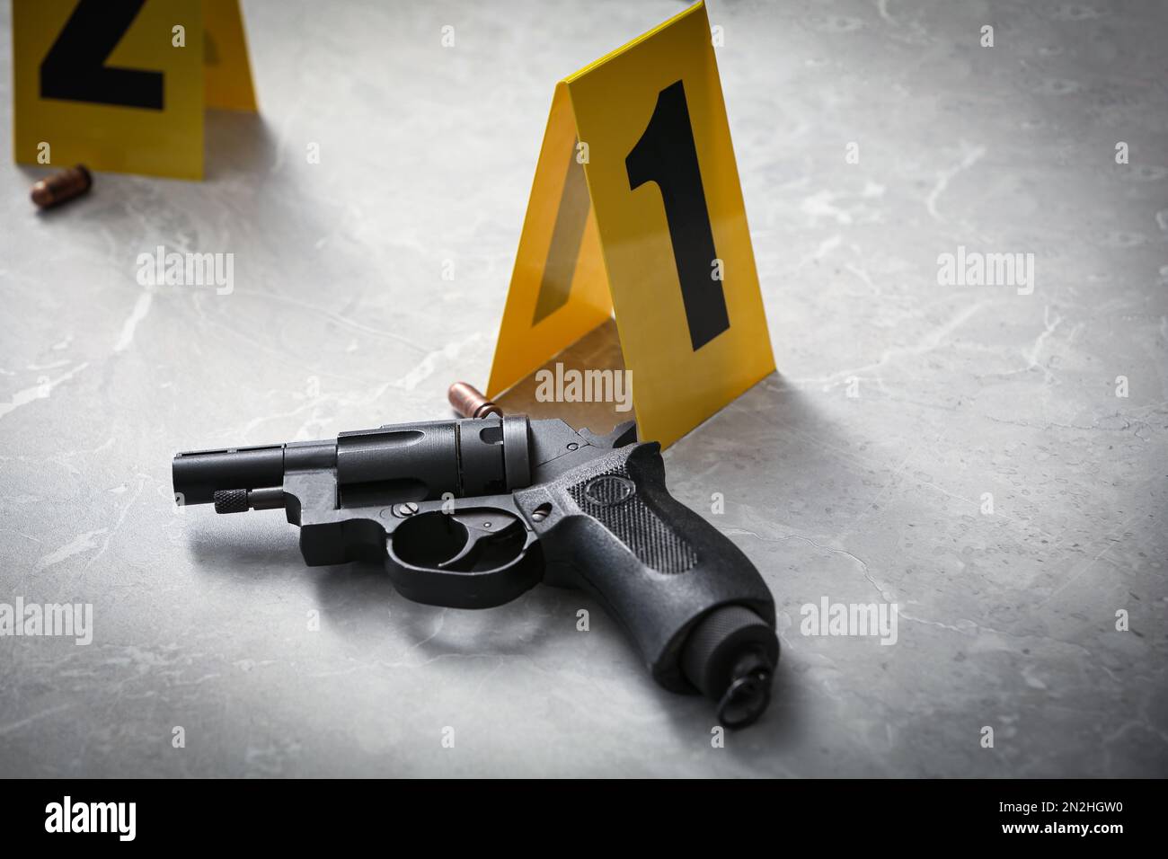 Pistola e pennarello scena del crimine su un tavolo in marmo grigio chiaro Foto Stock