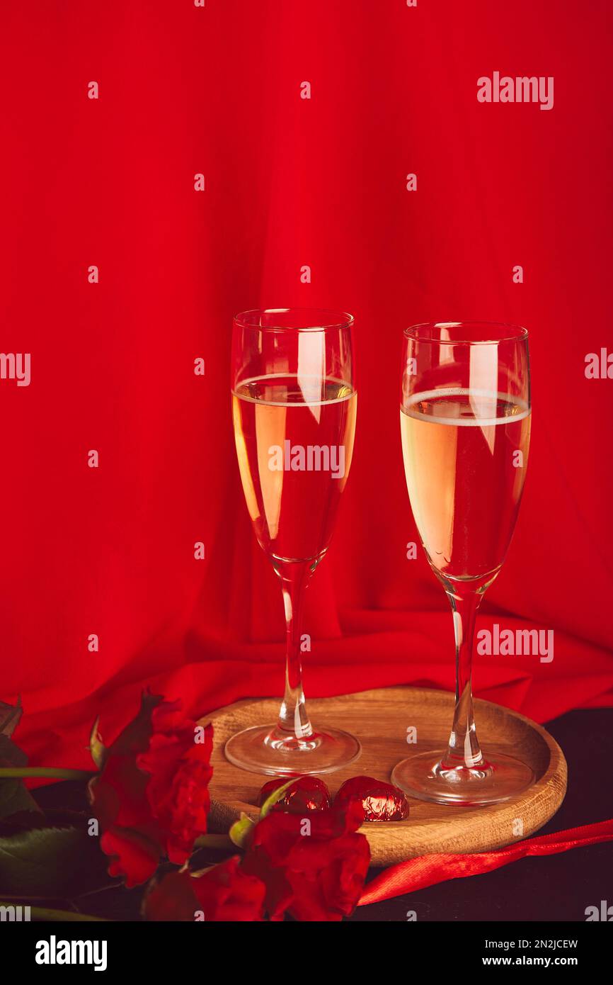 Tradizionale sfondo giorno di San Valentino. Rose rosse, champagne glasess, caramelle al cioccolato - cena romantica. Foto Stock