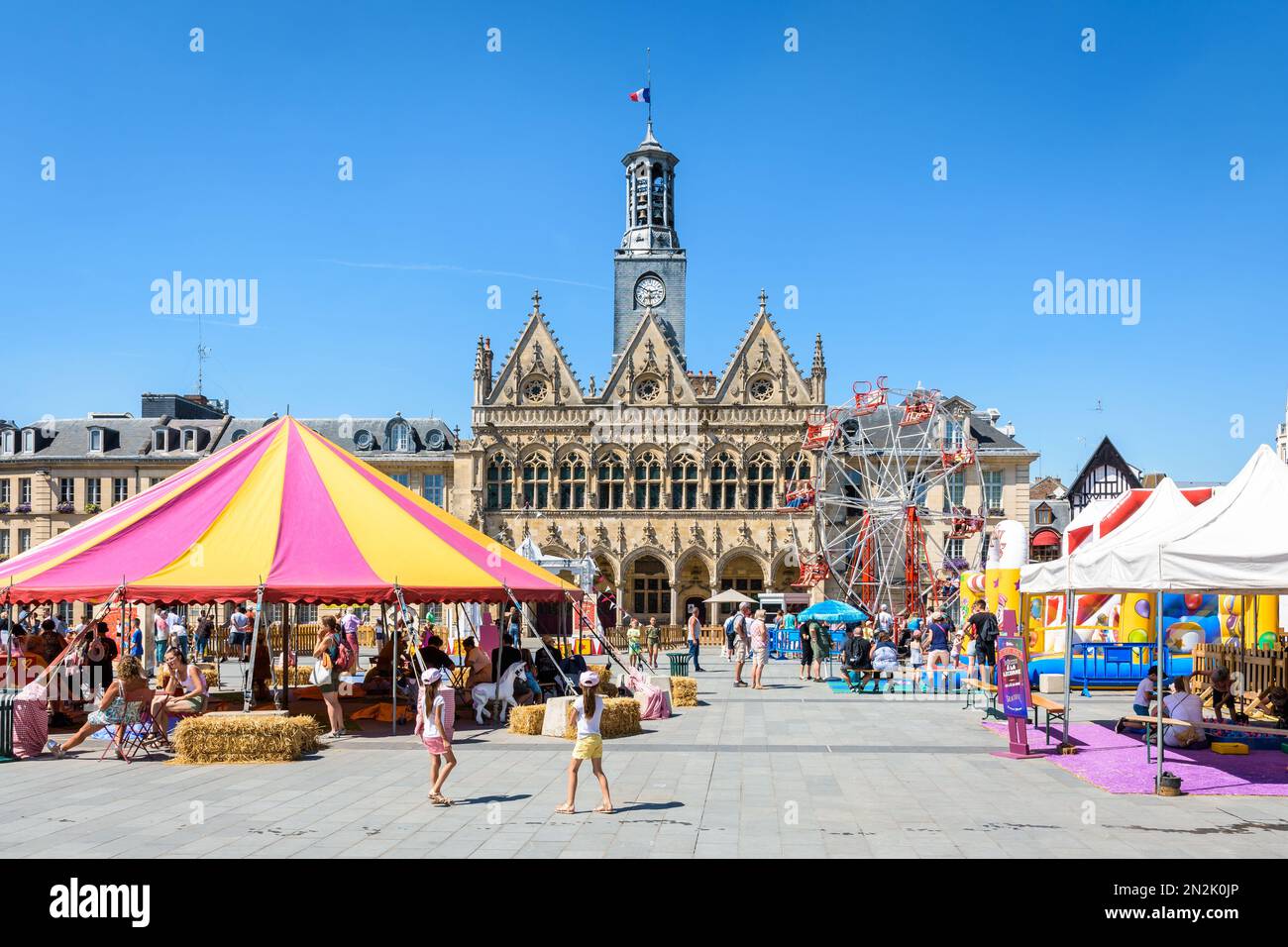Facciata in stile gotico del municipio di Saint-Quentin, Francia, con il Circus Parc intrattenimento estivo in primo piano in una giornata di sole. Foto Stock