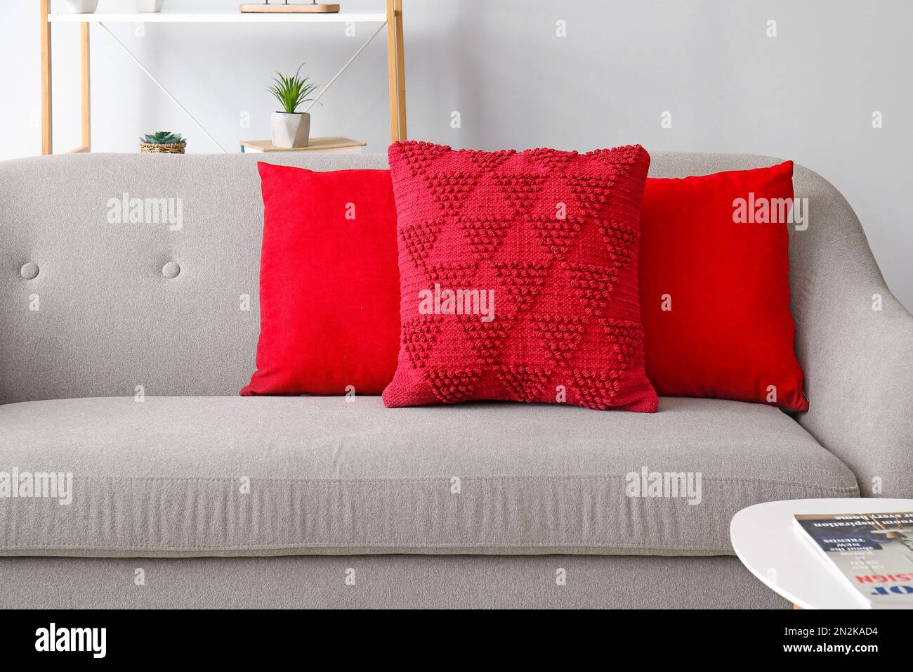 Cuscini rossi sul divano grigio nel soggiorno Foto stock - Alamy