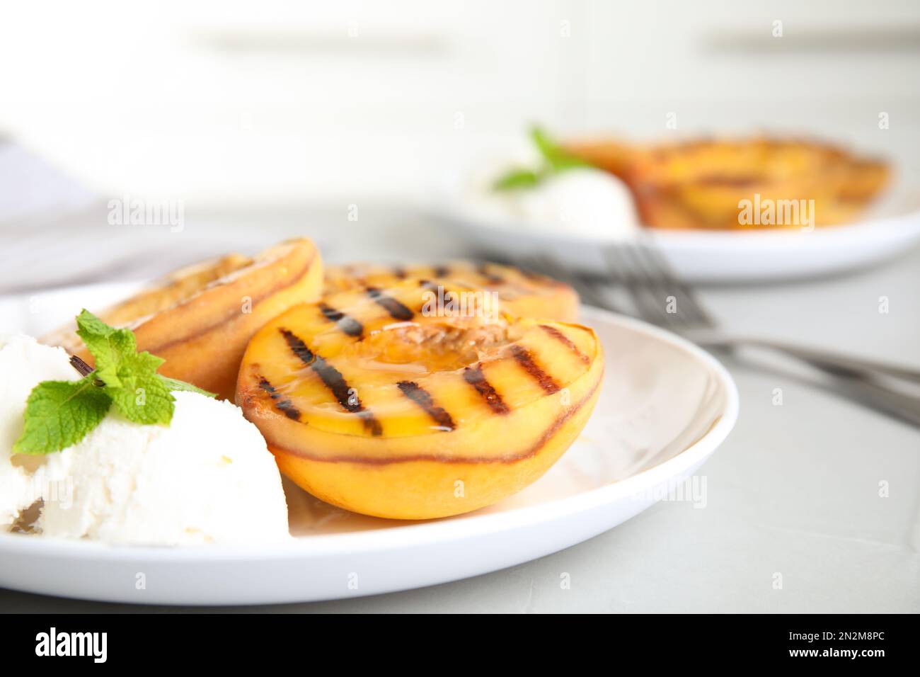 Deliziose pesche alla griglia con gelato e miele su tavolo grigio, primo piano Foto Stock