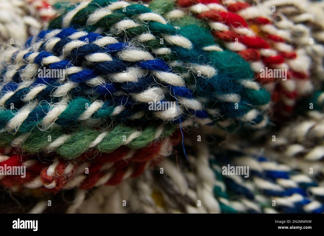 Primo piano di una matassa di filo di lana colorato filato a mano. Breve profondità di campo e messa a fuoco selettiva. Foto Stock