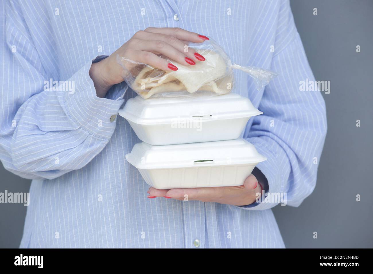 Mani di donna che tengono scatole da pranzo in schiuma da asporto. Contenitori per alimenti monouso, primo piano. Foto Stock