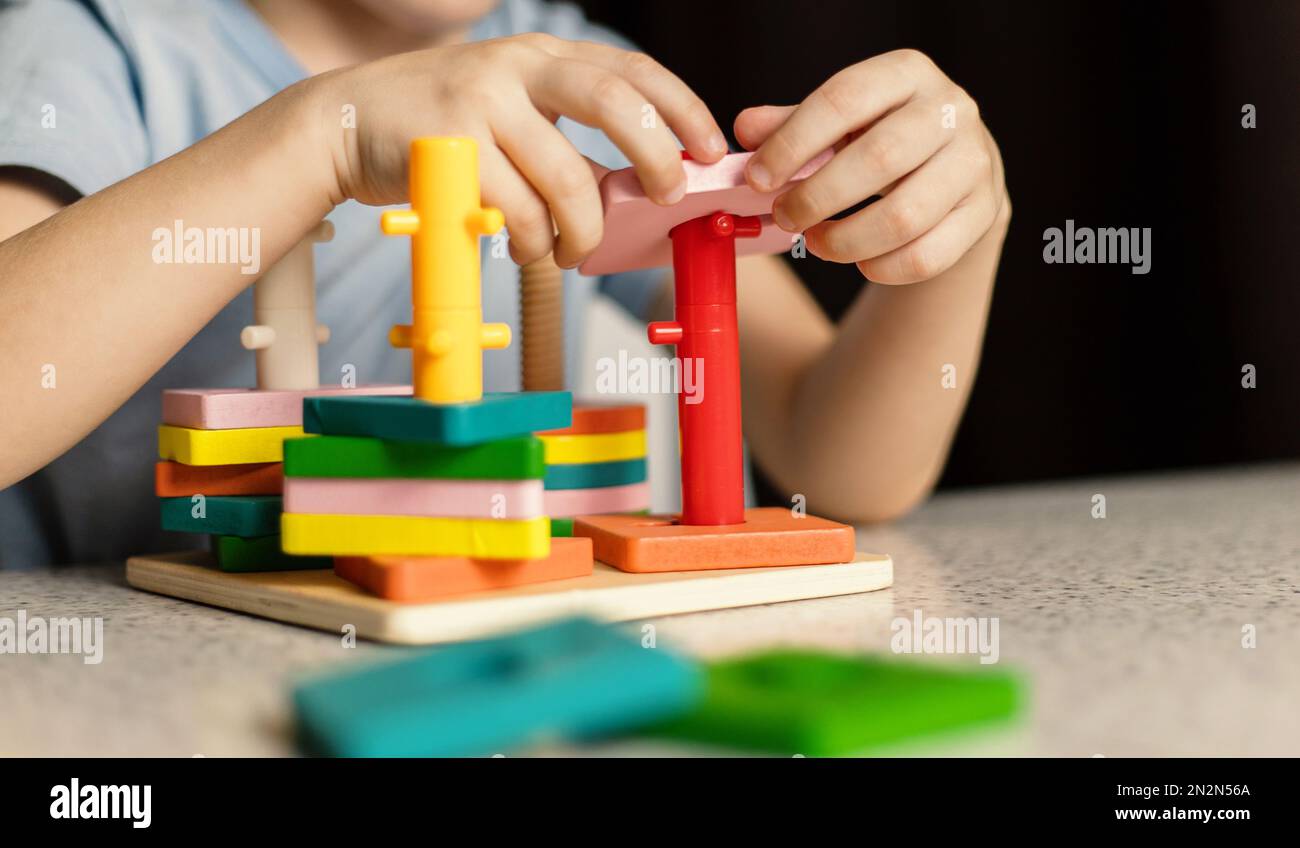 Primo piano delle mani dei bambini che giocano con un giocattolo educativo puzzle multicolore Foto Stock