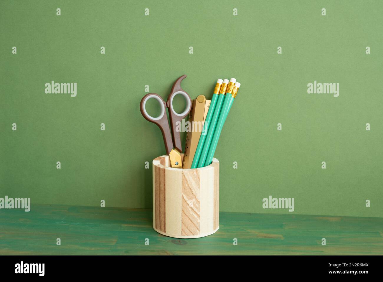 Portamatite su scrivania in legno. sfondo parete verde. spazio di lavoro, spazio di copia Foto Stock