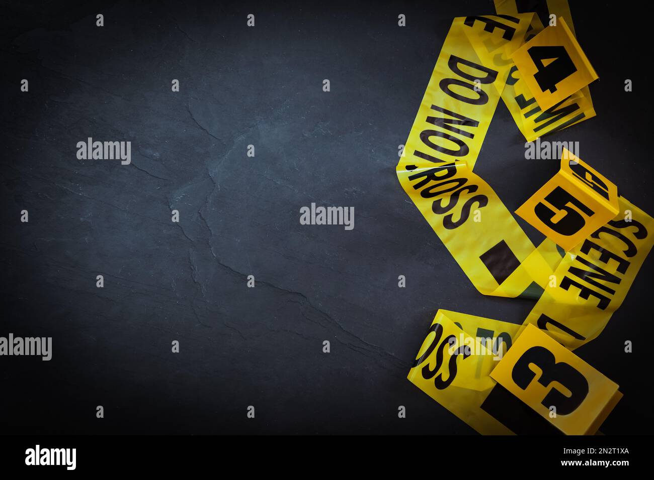 Nastro della scena del crimine e marcatori di prova su sfondo nero ardesia, piatto. Spazio per il testo Foto Stock