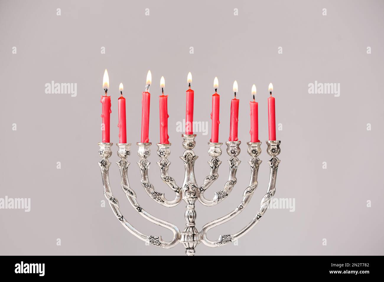 Menorah d'argento con candele accese su sfondo grigio chiaro. Hanukkah celebrazione Foto Stock