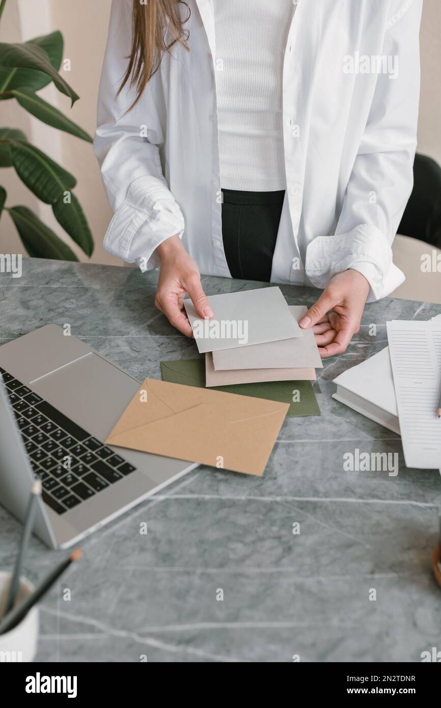 Primo piano di una donna in piedi su una scrivania che guarda i campioni di carta Foto Stock