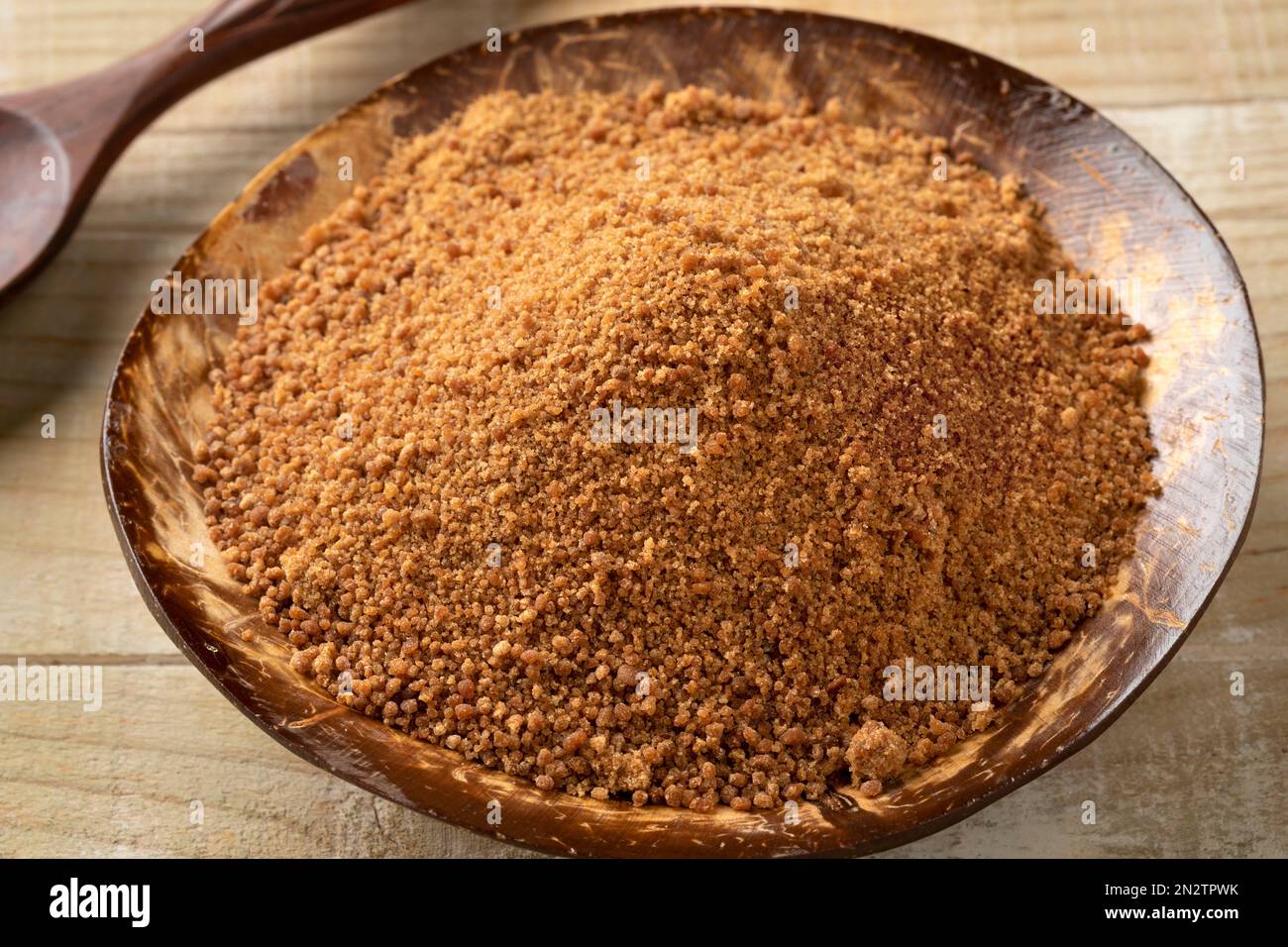 Ciotola di cocco con zucchero di palma dorato primo piano sul legno Foto Stock