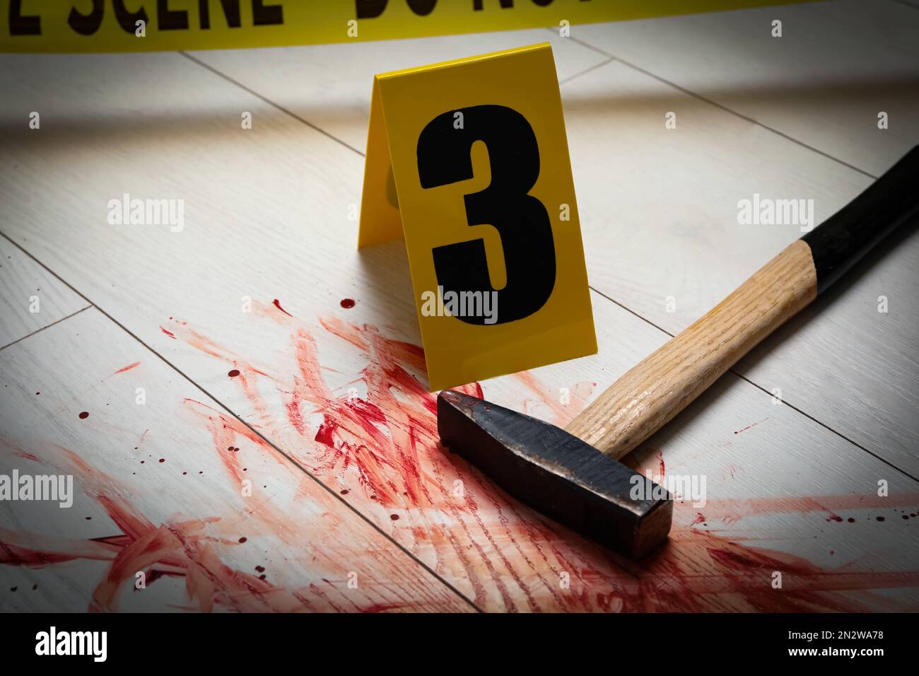 Martello nel sangue e marker scena del crimine su sfondo di legno bianco, primo piano Foto Stock