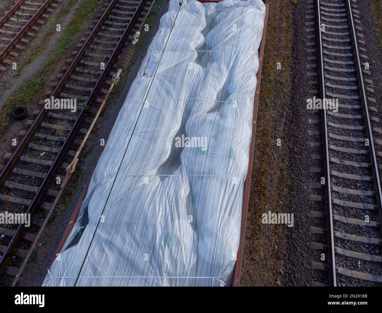 Vista dall'alto su un vagone ferroviario senza tetto carico di enormi sacchi bianchi e in attesa alla stazione nella città di Kyiv, Ucraina. Foto Stock