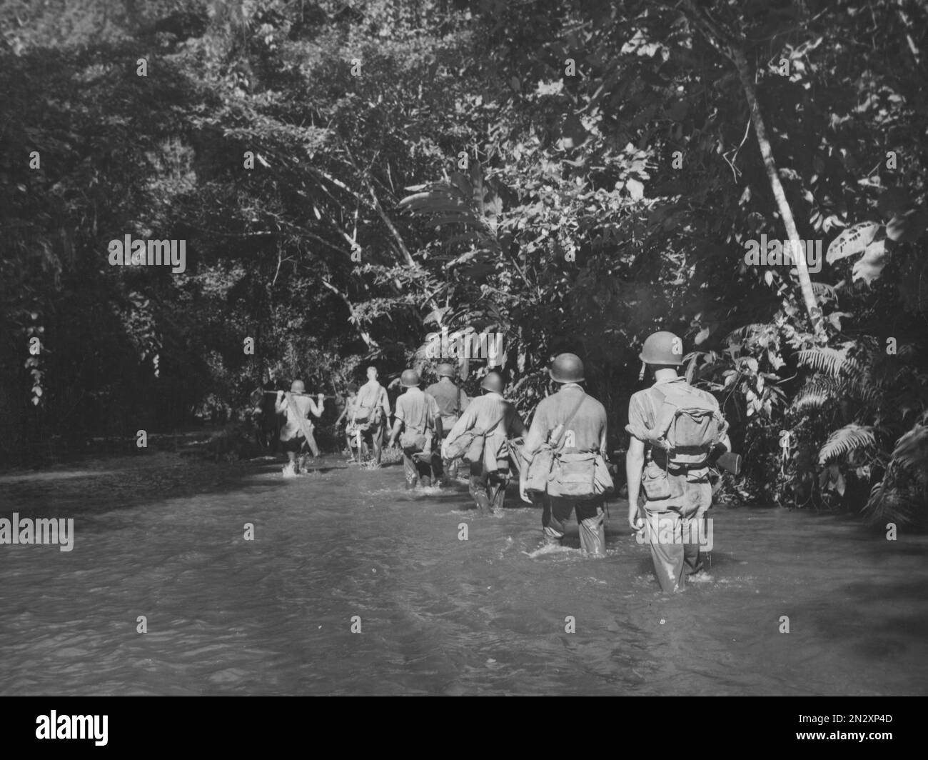 GUADALCANAL, Isole SALOMONE - circa 1942-1943 - i Marines statunitensi avanzano attraverso la fitta giungla del fiume Tenaru in una missione per distruggere due 77mm giapponesi Foto Stock